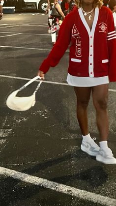 a woman in a red cardigan and white tennis skirt is holding a plastic bag