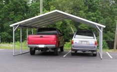 two trucks parked in a parking lot under a metal carport with trees in the background