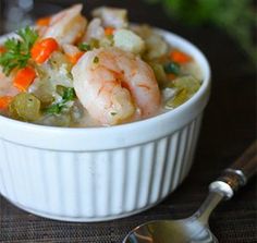 a white bowl filled with shrimp, carrots and celery next to a glass of wine