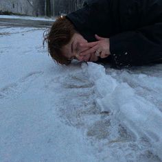 a woman is laying in the snow with her hands on her face