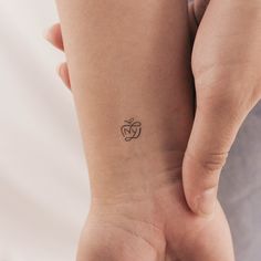 a woman's arm with a small tattoo on her left wrist and an apple in the middle