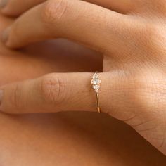 a woman's hand with a diamond ring on top of her finger, showing the side view