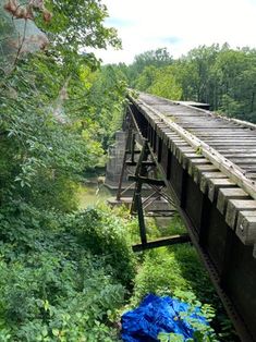 a blue tarp is on the side of an old bridge over water with trees in the background