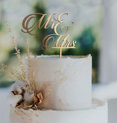 a white wedding cake with gold lettering on top