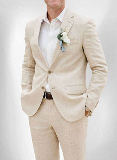 a man in a tan suit and flower boutonniere is posing for the camera