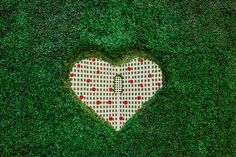 a heart made out of white and red checkered fabric on top of green grass