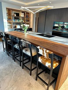 a modern kitchen with an island and bar stools in front of the countertop