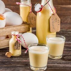 two glasses filled with milk sitting on top of a table next to bottles and cinnamons