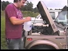 a man standing next to a car with the hood open