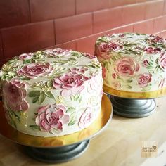 two cakes sitting on top of metal pans covered in frosting and pink flowers