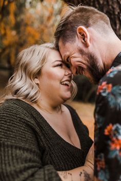 a man and woman laugh together in front of a tree