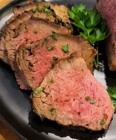 two pieces of meat on a plate with some parsley and green garnish