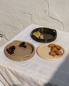 there are two plates with food on them and one plate has grapes in it, while the other is empty