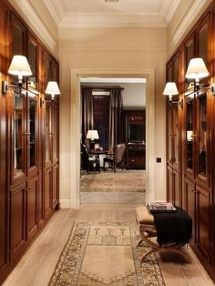 the hallway is lined with wooden paneling and lamps on either side of the door