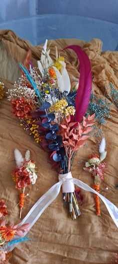 an arrangement of flowers and feathers on a bed