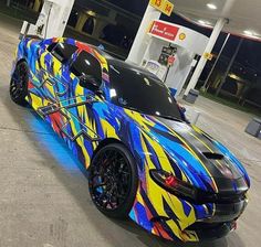 a blue and yellow car parked in front of a gas station with graffiti on it