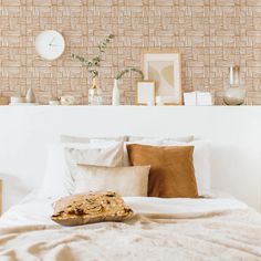 a bed with white sheets and pillows in front of a wallpapered headboard