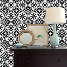 a black and white wallpaper with an ornate design on the wall next to a dresser