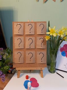 a wooden easel with question marks on it next to some flowers and other crafting supplies