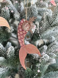 a christmas ornament hanging from a tree with pine cones and glitters on it