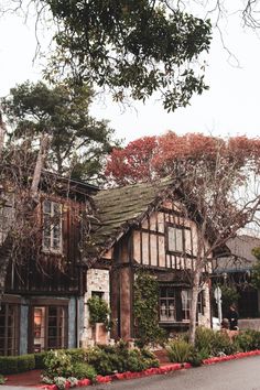 an old house with flowers and trees around it