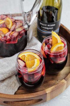 two glasses filled with red wine and orange slices