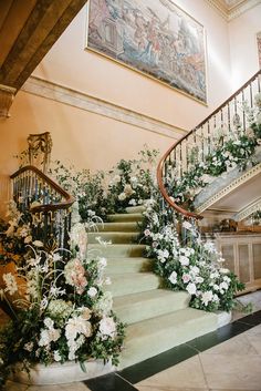 a staircase decorated with flowers and greenery next to a set of banisters