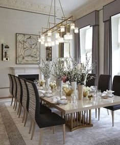 a dining room table with black chairs and white flowers on the centerpiece in front of it