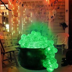 a pot full of glowing green bubbles in front of a halloween themed house with lights