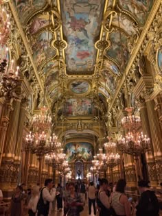 people are standing in an ornate room with chandeliers and paintings on the ceiling