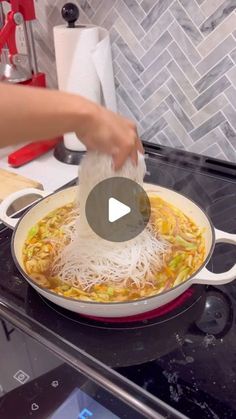 someone is adding noodles to a skillet on the stove