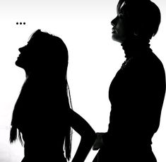 two women standing next to each other in silhouette