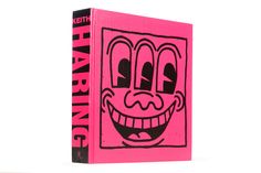 a pink book with an image of a smiling clown's face on the cover