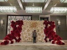 a man standing in front of a giant flower wall with red and white flowers on it