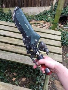 someone is holding a large knife on top of a wooden bench in front of a fence