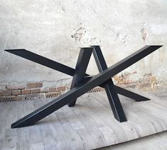 a black metal table sitting on top of a wooden floor next to a brick wall