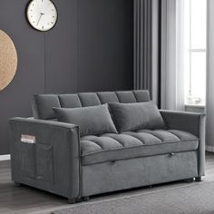 a living room with a gray couch and clock on the wall