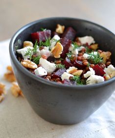 a bowl filled with beets, nuts and feta cheese on top of a table