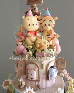 a birthday cake with winnie the pooh figurines on top and decorations around it