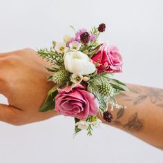 a person's hand holding a bouquet of pink and white flowers on their wrist