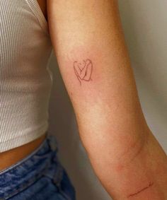 a woman's arm with a small heart tattoo on it