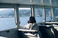 a woman sitting on the back of a boat looking out at the water