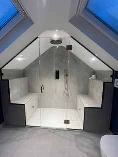 an attic bathroom with skylights and a walk in shower