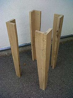 three wooden posts are standing next to each other on the ground in front of a white wall