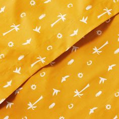 a yellow sheet with white arrows and stars on it is laying down next to a pillow