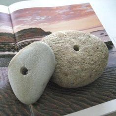 an open book with two rocks sitting on it's cover and the pages are covered in sand