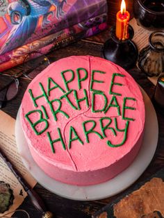 a pink birthday cake with the words happy birthday harry written on it and some books