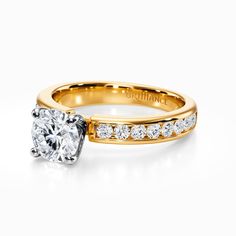 a diamond engagement ring with channel set diamonds on the band and side stones in yellow gold