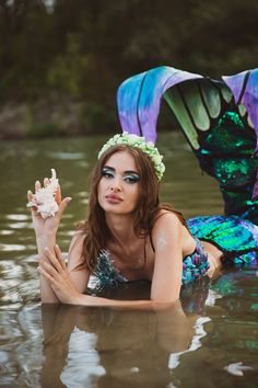 a woman in a body of water with two mermaids on her head and one holding a seashell