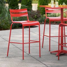 three red metal bar stools sitting next to each other on top of a patio